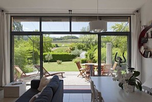 A modern living room with a large glass door leading to a garden. - Detached house, quiet, beautiful garden, mini pool, Drôme provençale, 2 Pers (Vinsobres)