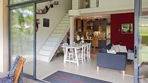 Moderni sisustus, jossa on portaikko, joka johtaa toiseen kerrokseen, valkoisilla huonekaluilla sisustettu ruokailutila ja punainen tehosteseinä.