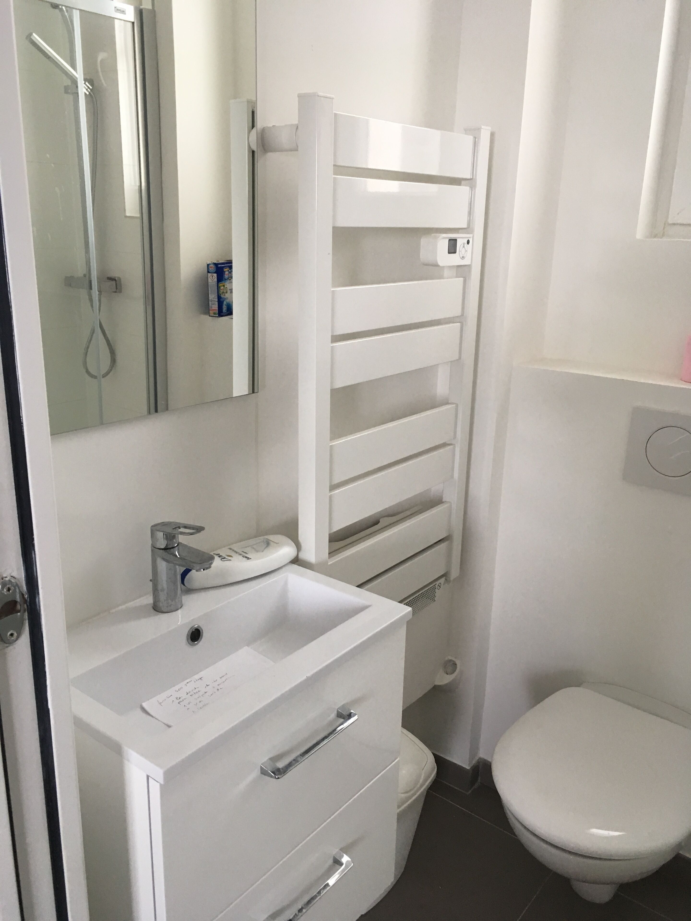 A bathroom with a white sink, mirror, and toilet.