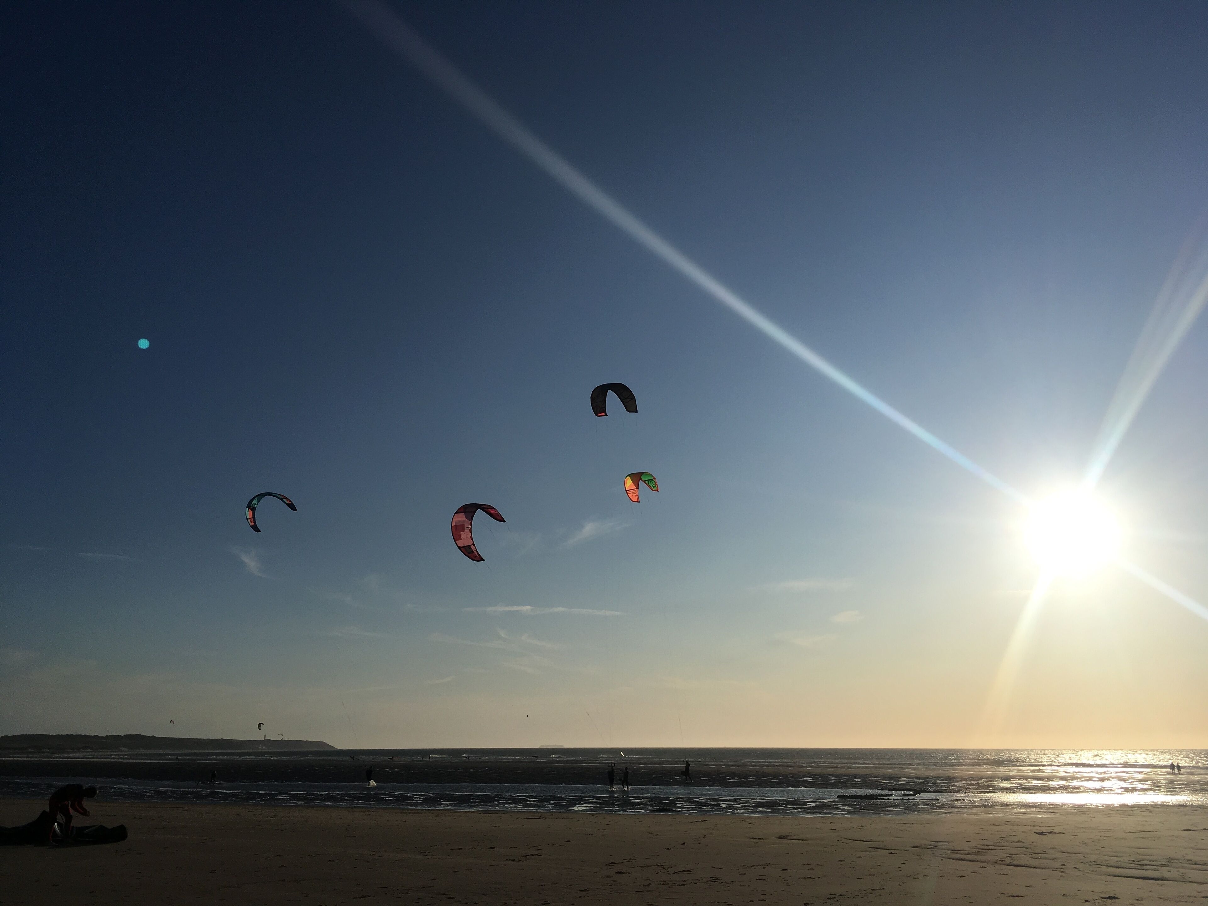 A beach with a clear sky and the sun low on the horizon.