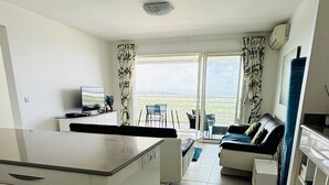 A modern, well-lit room with a kitchen area, a dining table, and a sofa. - Luxury apartment with splendid sea view (Case-Pilote)