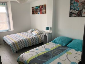 Une chambre avec deux lits, une fenêtre et une œuvre d’art accrochée au mur.