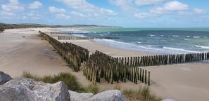 A beach with wooden groynes, a sandy shore, and waves.