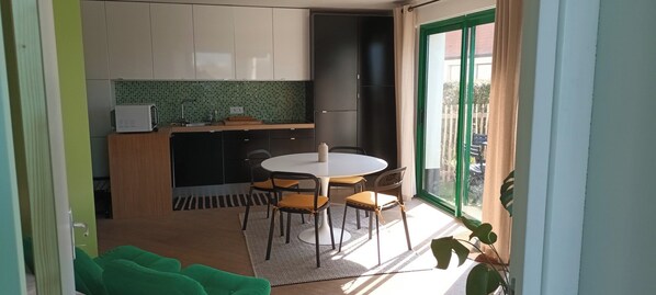Eine kleine Küche mit Essbereich, einem Kühlschrank und einem fensterbepflanzten Fenster.