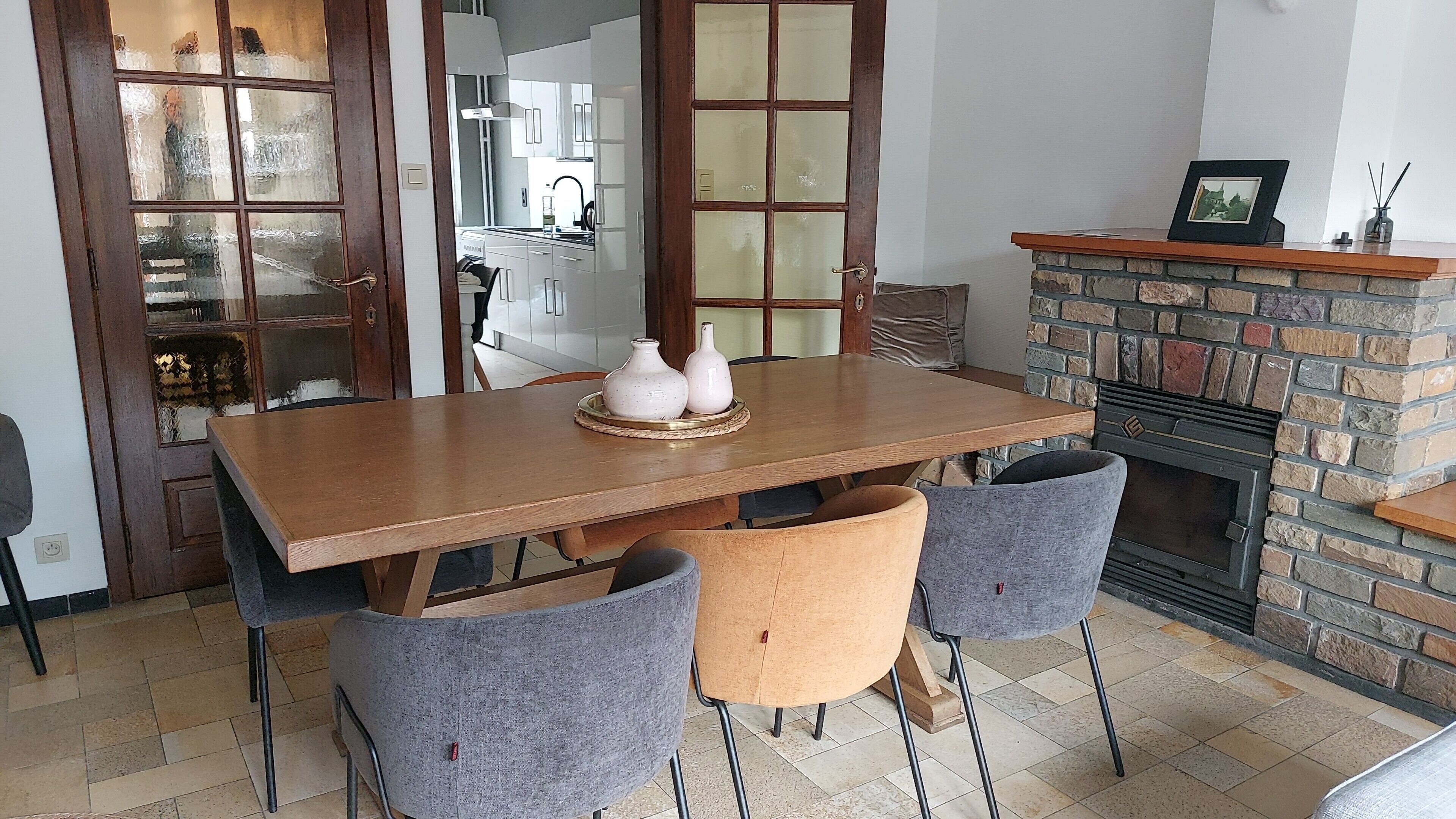 Un coin repas comprenant une table en bois, quatre chaises et une cheminée avec un manteau en pierre.