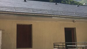 Ein Gebäude mit einem Ziegeldach, zwei Türen und einem Tisch mit Stühlen.