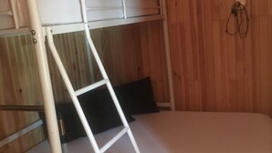 Ein Stockbett mit einer Leiter, einem Kopfkissen und einem an der Wand befestigten Haken.