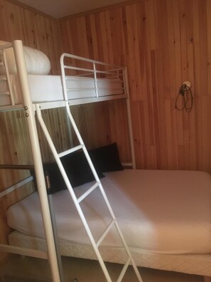 Een stapelbed met een ladder, een kussen en een haak aan de muur.