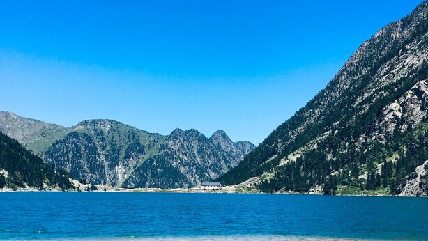 Ein See, umgeben von Bergen, mit blauem Himmel.