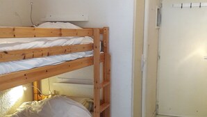 A room with a bunk bed, a door, and tiled flooring.