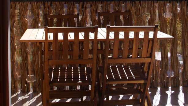 A wooden table and chairs on a balcony with a view of mountains. - SPACIOUS STUDIO 30M2 balcony south facing terrace 4 pers near downtown (Barcelonnette)