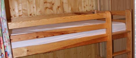 A bunk bed with a wooden headboard and a lower bunk with a mattress.