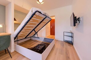 Une pièce compacte comprenant un lit en mezzanine, un bureau et une petite étagère.
