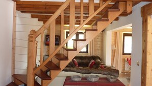 A wooden staircase leading to a loft area with a fur-covered sofa and three woven baskets on a table.