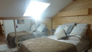 A bedroom with two beds, a skylight, wooden walls, and a mirror.
