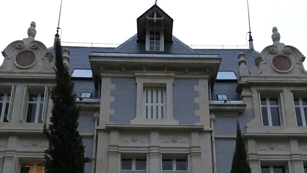 A large, stately building with a symmetrical facade, multiple windows, and a central entrance with steps leading up to it.