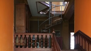 A wooden staircase with ornate balustrades and a metal spiral staircase above.
