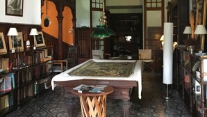 A room with a large central table, wooden bookshelves, and a patterned floor.