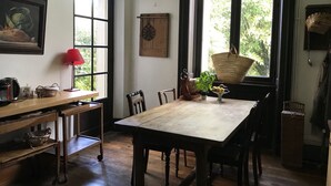 A dining area with a wooden table and chairs, a red lamp, a basket, and a potted plant.