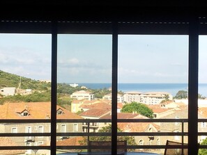 A view from a window overlooking a coastal town with buildings and a sea in the background. - NEW 2-ROOM APARTMENT WITH SEA VIEW (Propriano)