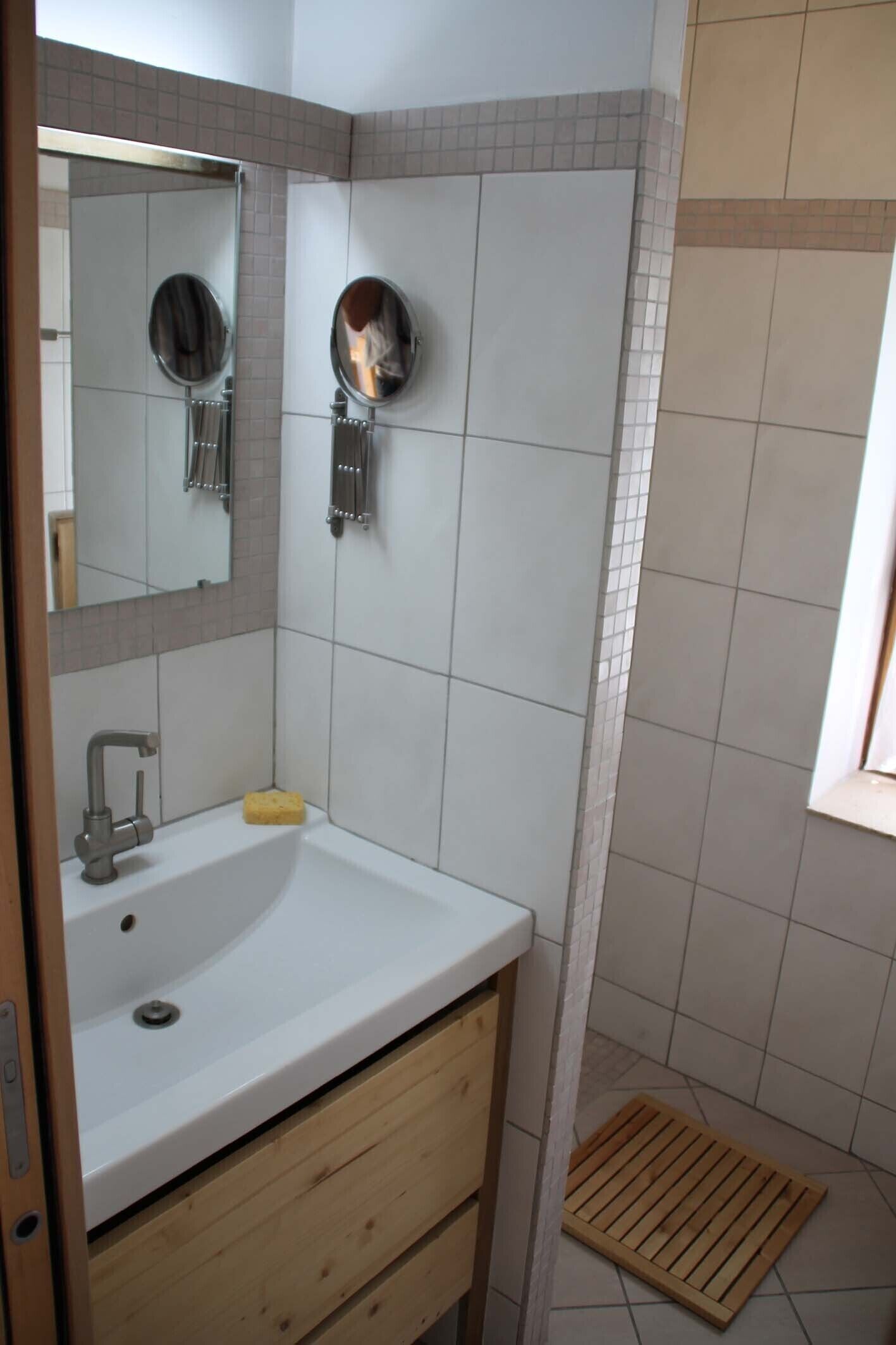 A bathroom with a white sink, a mirror, and a shower area.
