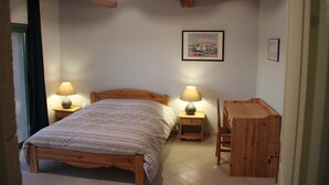 Une chambre à coucher avec un lit en bois, deux tables de chevet avec des lampes, un bureau en bois et un tableau encadré au mur.