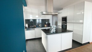 A modern kitchen with white cabinetry, a central island, and stainless steel appliances. - Fully renovated apartment, in the Centre of Funchal. AMAZING view (Funchal)