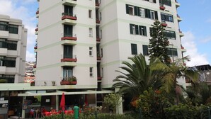 A multi-story hotel with balconies, a covered outdoor seating area, and lush landscaping. - Fully renovated apartment, in the Centre of Funchal. AMAZING view (Funchal)