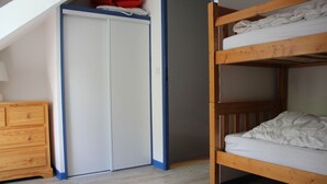 A room with a bunk bed, a wooden dresser, and a wardrobe with a blue trim.