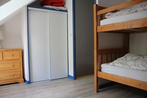 Una habitación con una cama litera, un aparador de madera y un armario con detalles azules.