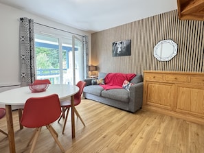 Una sala de estar moderna con un sofá gris, sillas rojas, una mesa blanca y un aparador de madera.