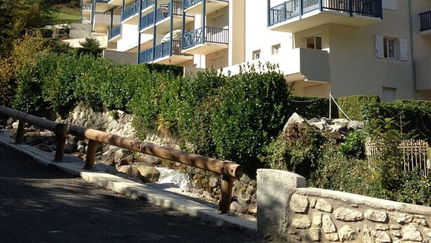 A multi-story hotel with balconies, set against a mountainous backdrop.