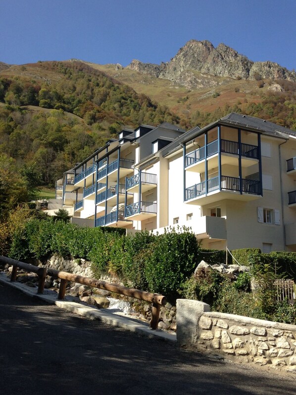 Un hotel de varios pisos con balcones, con montañas al fondo.