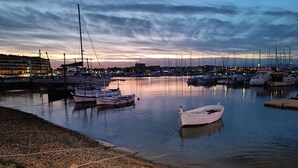 Un port de plaisance où sont amarrés plusieurs bateaux, avec une eau calme et une vue sur la ville en arrière-plan.