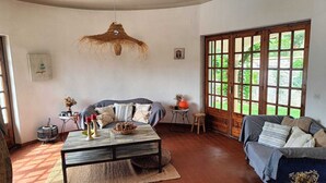Un salon confortable avec un canapé, une table basse et une grande fenêtre donnant sur un paysage verdoyant.