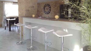 Eine moderne Küche mit Barbereich, mit einer Wand aus Stein, einer Uhr und einem Blumentopf.