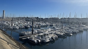 A marina with numerous boats docked, a bridge, and a tower in the background. - Magnificent villa with heated pool close to beaches (Arzon)