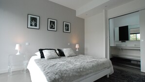 A modern bedroom with a large bed, bedside lamps, and a TV on a stand. - Magnificent villa with heated pool close to beaches (Arzon)