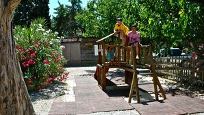 A wooden play structure in a park with a gravel path and a sign that reads "SERVICETOWN". - Algajola - New wooden air-conditioned chalet for 4/5, 1 km away from the beach (Algajola)