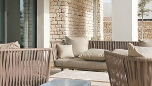 A modern outdoor seating area with a stone wall backdrop, a sofa, and two armchairs. - Luxurious villa with sea views in Essaouira (Essaouira)