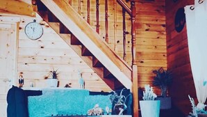 Una escalera de madera con un reloj, un sofá azul y una mesa de centro en una habitación de estilo rústico.