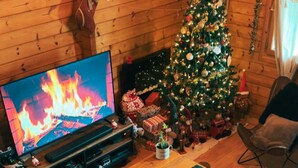 Una sala de estar acogedora con un televisor de pantalla plana grande, una mesa de centro de madera y un árbol de Navidad.