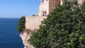 A coastal building with a stone wall and balconies overlooking the sea. - MINI VILLA in Corsica (Lecci)