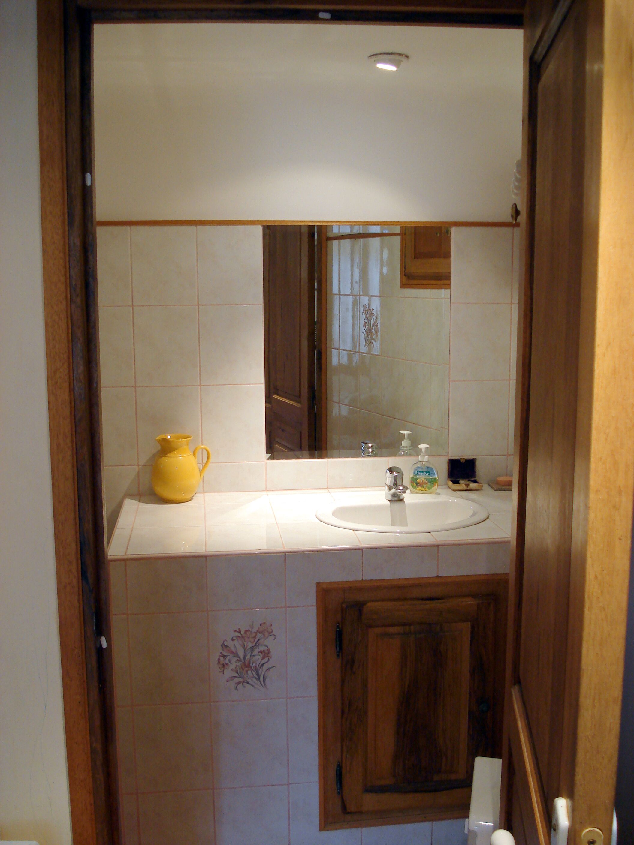 Une salle de bain avec un lavabo, un miroir et un meuble en bois.