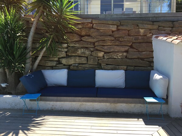 A stone wall, a blue sofa with cushions, and a small blue table. - Villa, with swimming pool not overlooked, beach 10min walk, close to activities (Saint-Cyr-Sur-Mer)