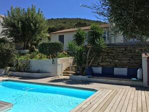 A swimming pool with a wooden deck, surrounded by greenery and a stone wall. - Villa, with swimming pool not overlooked, beach 10min walk, close to activities (Saint-Cyr-Sur-Mer)