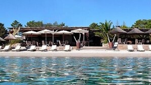 A poolside area with lounge chairs and umbrellas, a building with a thatched roof, and a clear blue pool. - San Cipriano (St Cyprien) 6 pers conditioned villa, in residence (Lecci)