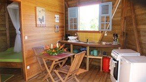 Ein gemütliches Holzhaus mit Essbereich, einer kleinen Küche und einem Schlafbereich mit Baldachinbett.