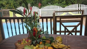 Ein Holztisch mit Obstkorb, Blumenvase und einer Auswahl an Obst und Gemüse.