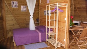 Ein Zimmer mit Holzboden, einem Bett, einer Holzregalanlage, einem Schreibtisch und einem Stuhl.